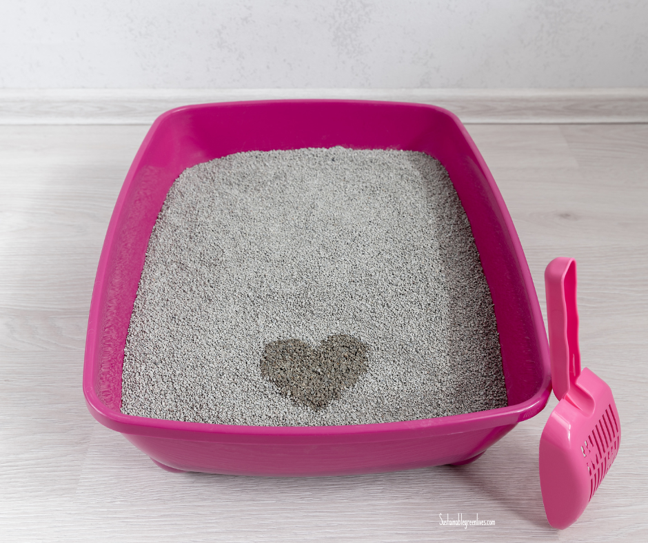 A pink litter box filled with gray cat litter. The cat litter has a heart-shaped wet spot in the center. There's a pink litter scoop resting next to the litter box. The background features a light-colored wooden floor and a plain white wall. A pink litter box filled with gray cat litter. The cat litter has a heart-shaped wet spot in the center. There's a pink litter scoop resting next to the litter box. The background features a light-colored wooden floor and a plain white wall.